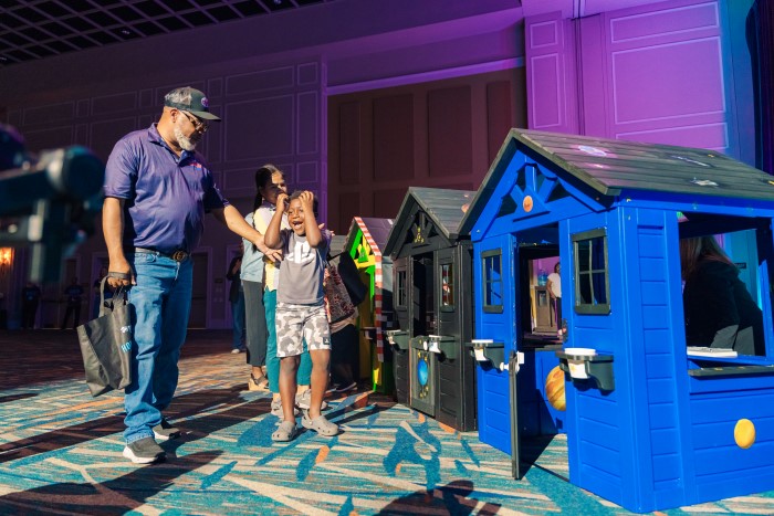 A man walks alongside an excited child next to a collection of small wooden plastic homes