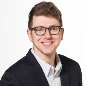 ma with glasses and a suite smiling