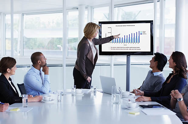 women presenting data in a meeting room full of people